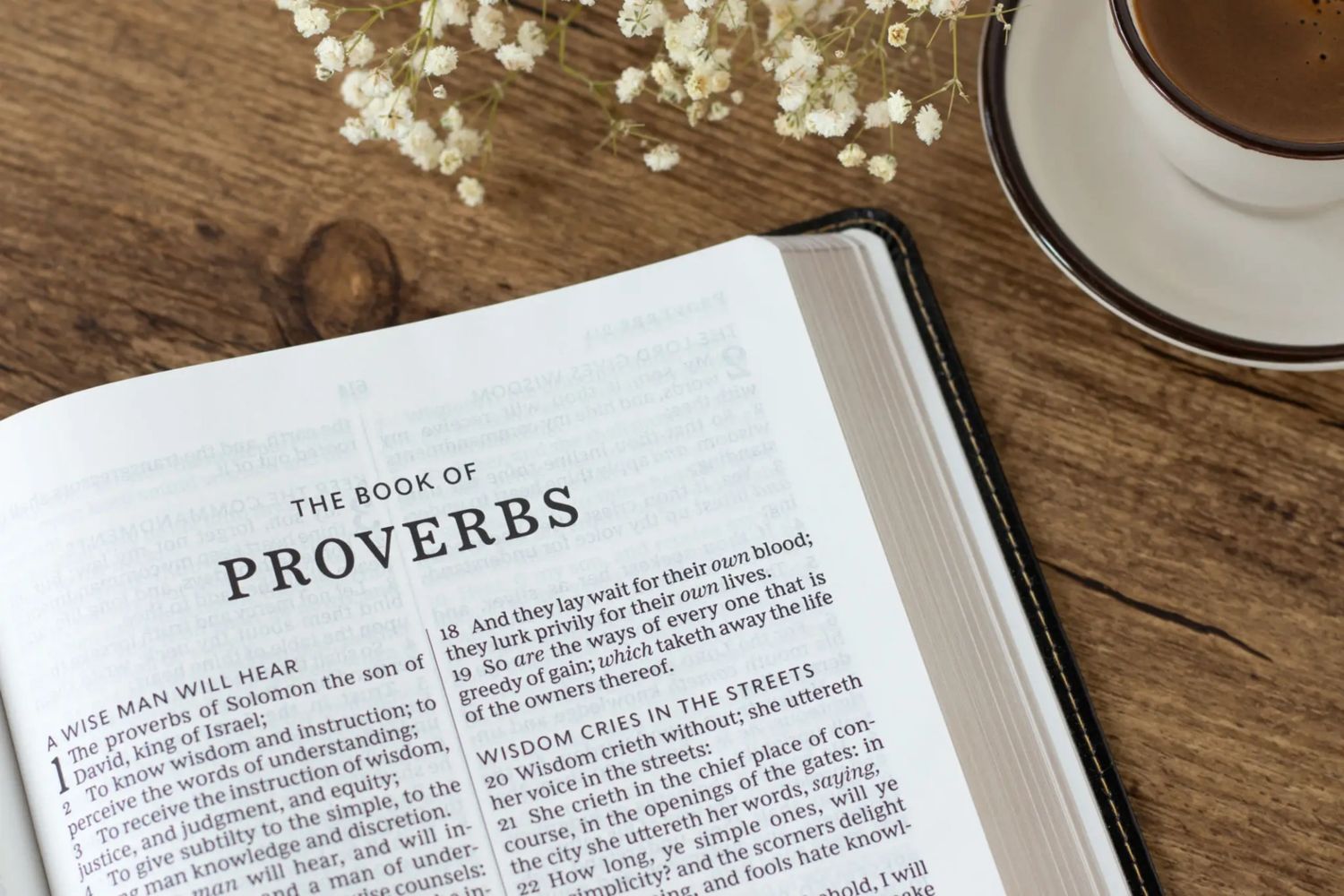 Coffee time with open Bible on dark wooden table.