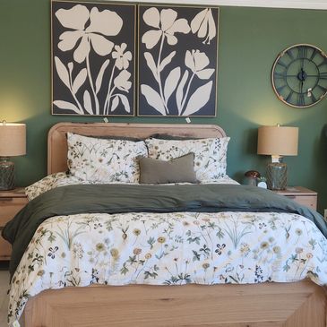 Cozy bedroom with green walls, floral bedding, and wooden furniture.