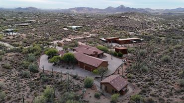 Desert houses surrounded by cacti and mountainous landscape.