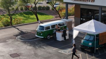 People at an outdoor coffee van booth setup.