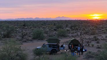Camping at sunset in a desert with mountains.