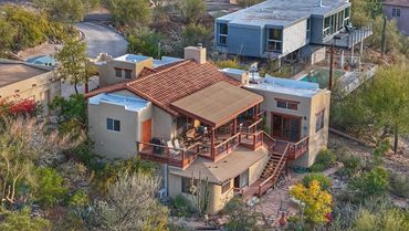 A tan desert-style house with a spacious wooden deck.