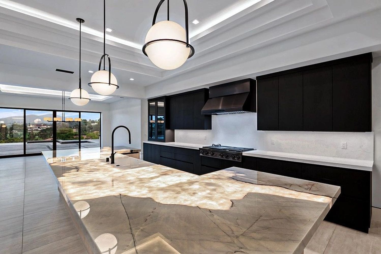 Modern kitchen with black cabinets and illuminated marble island.
