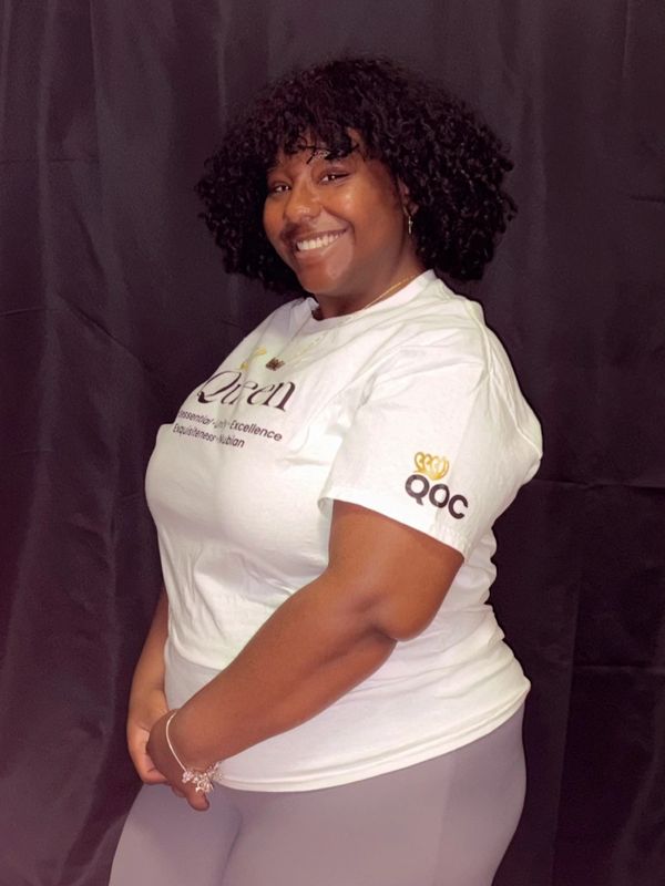 Smiling woman in white T-shirt and gray pants.