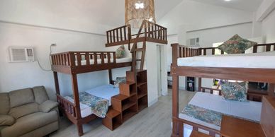 Cozy room with multiple wooden bunk beds and a sofa.