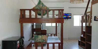 Compact room with wooden bunk beds and a microwave on a small table.