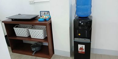 Office corner with a wooden shelf and water dispenser.