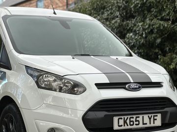 White Ford vehicle with racing stripes parked outdoors.