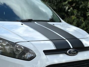 Close-up of a white Ford car with black racing stripes on the hood.