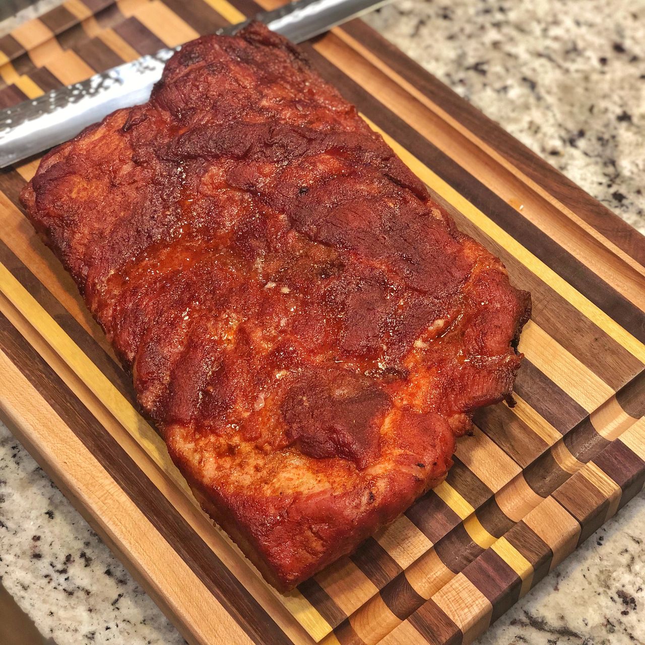 A slab of pork belly after smoking on a cutting board. 