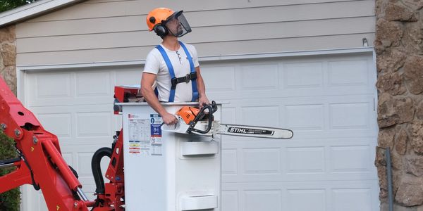 Man in a bucket lift with a chainsaw.