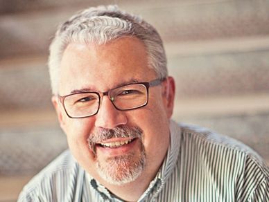 Smiling middle-aged man with glasses and gray hair.