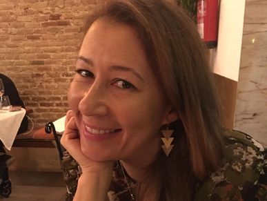 Smiling woman resting her chin on her hand in a cozy restaurant.