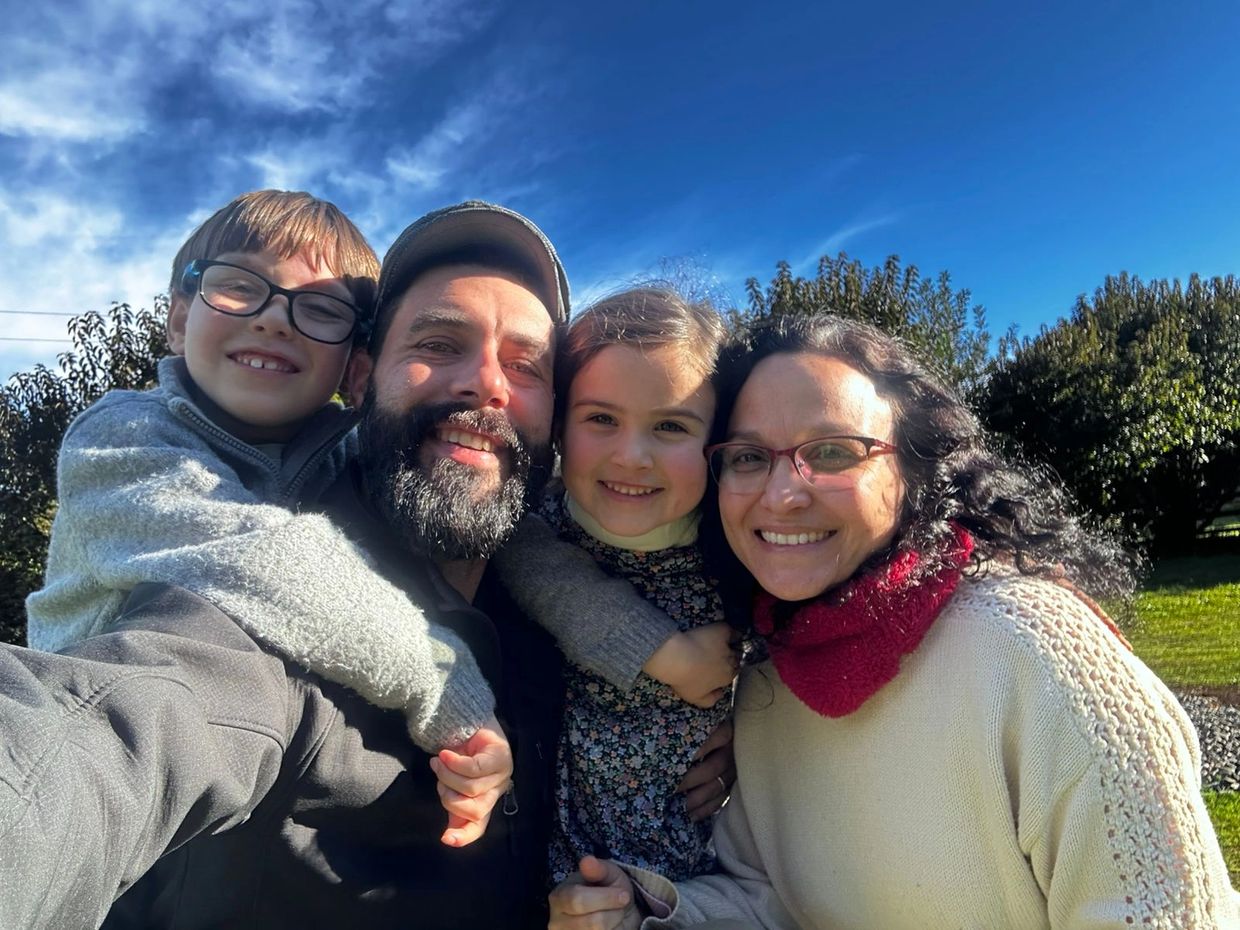 Happy family selfie outdoors under a clear blue sky.