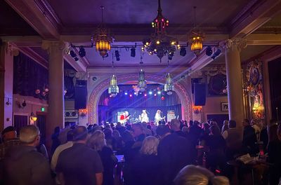 Crowded music venue with live band performing under warm lights.