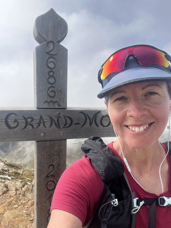 Jen Benson at the top of a European Mountain top having taken a selfie. 