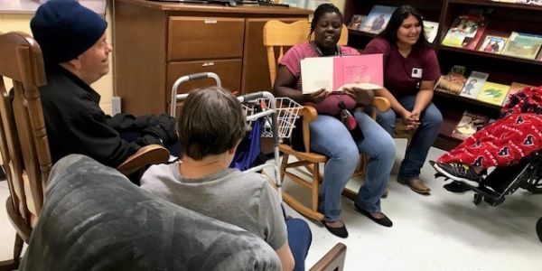 Woman reading book to group in library.