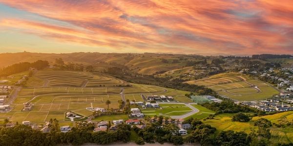 Sunset over a scenic valley with rolling hills and a residential area.