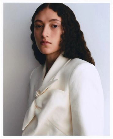 Woman with long curly hair in a white garment.