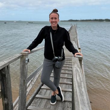 Smiling woman standing on wooden pier by the water.