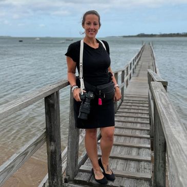 Woman posing on a wooden pier by the water.