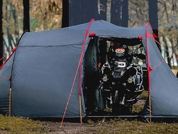 A tent with a motorcycle partially inside it, set outdoors.