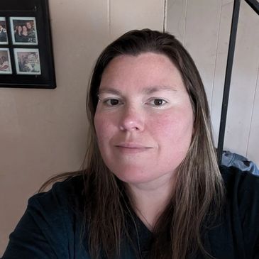 Woman with long brown hair taking a selfie indoors.