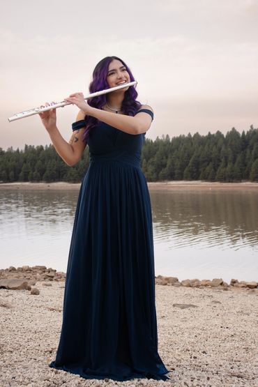 Woman playing the flute in front of a lake