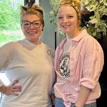 Two smiling women posing indoors with casual outfits and headbands.