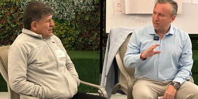 Two men engaged in a serious conversation indoors.