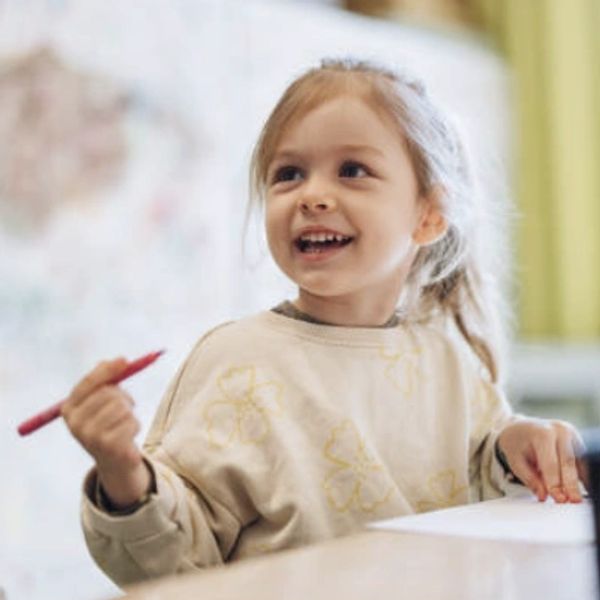 Little girl engaged in learning smiling at teacher