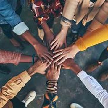 Diverse group joining hands in unity and teamwork.