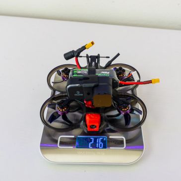 A small drone on a digital scale showing 216 grams.