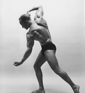 Black and white photo of a muscular man posing.