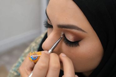 Close-up of woman applying eye makeup with brush.