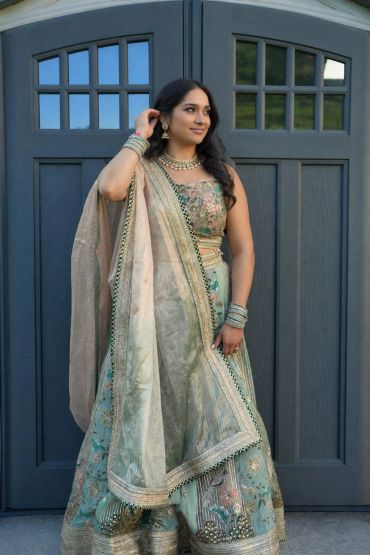 Woman in traditional embroidered outfit standing by a door.