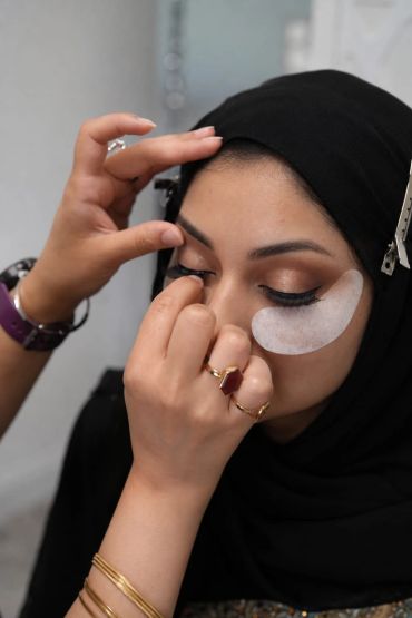 Woman getting eye makeup applied with under-eye patches.