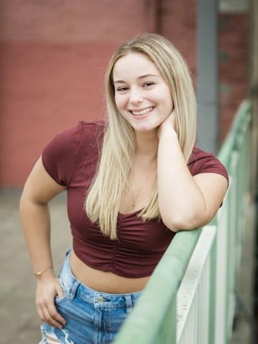 Young woman smiling, leaning on a railing outdoors.
