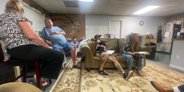 A group of people sitting and engaging in a discussion in a cozy living room.