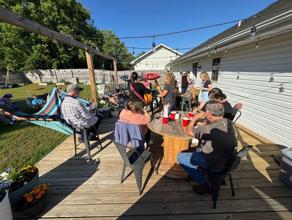 Group enjoying a sunny backyard gathering with music and drinks.