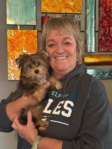 Woman holding a small dog, both smiling.