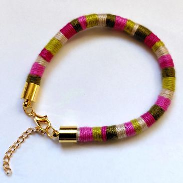 A vibrant  coloured handmade thread wrapped bracelet with a gold coloured clasp. Available online.