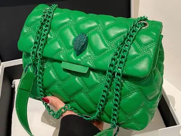 A vibrant green quilted handbag with chain straps and a decorative clasp.