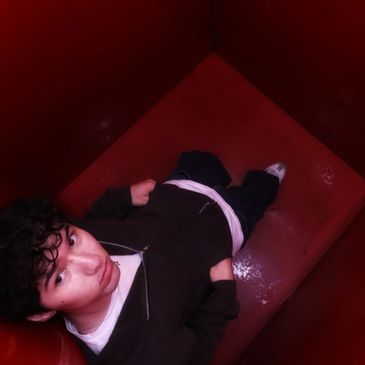 Person sitting in a red corner booth, looking up.