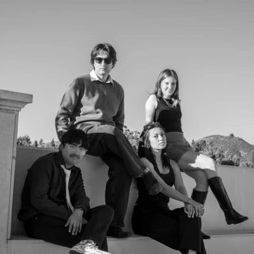 Four young adults posing outdoors in black and white photo.