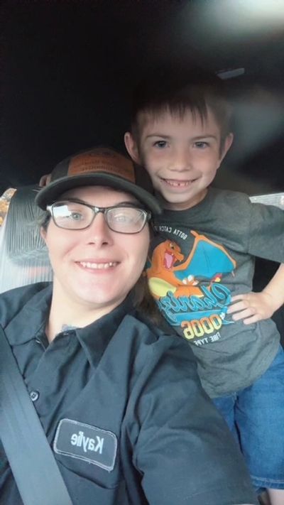 A smiling woman and young boy posing together inside a vehicle.