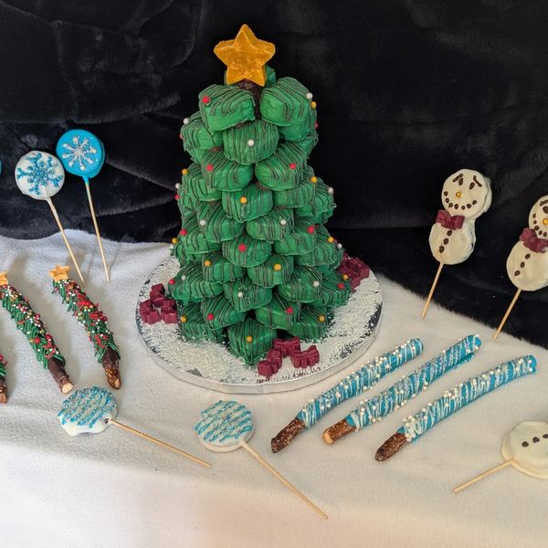 A festive Christmas tree dessert surrounded by holiday-themed treats.