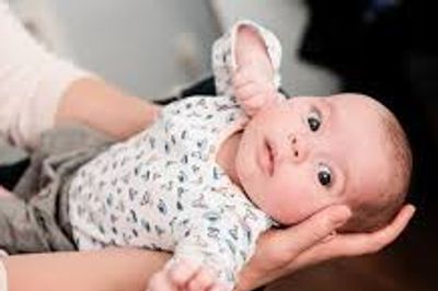 A baby being gently held and comforted by an adult.