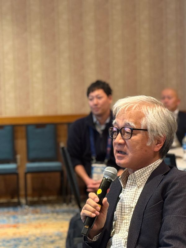 Elderly man speaking into microphone.