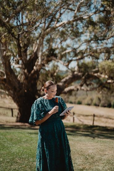 Woman in a green dress enjoying ice cream and using a tablet outdoors.